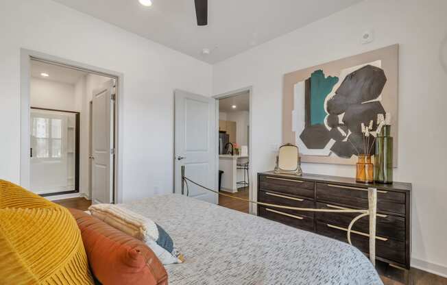a spacious bedroom with a bed, dresser, and painting at Apex apartments in Colorado Springs, CO