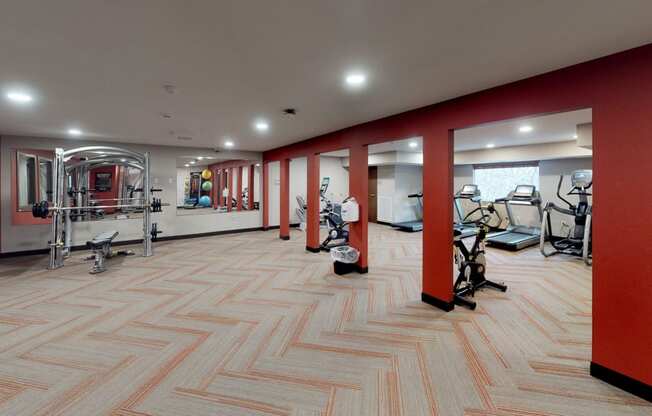 a gym with red walls and a wood floor with exercise equipment