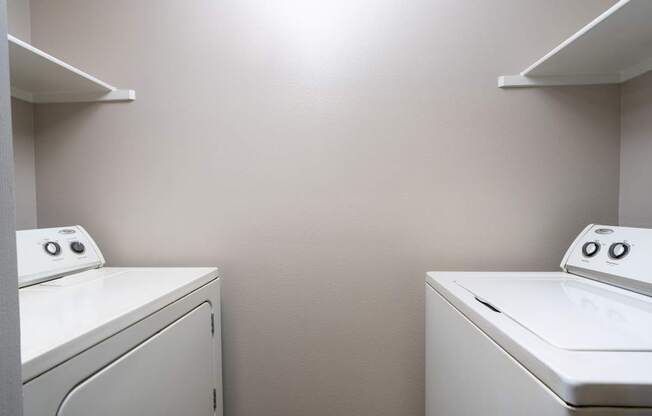 Two white washing machines in a laundry room.