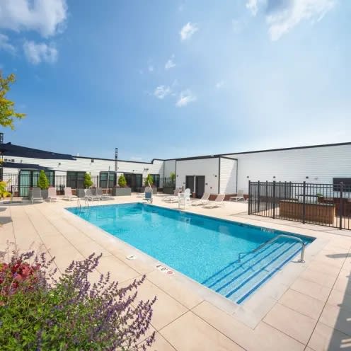 a swimming pool with chairs around it in front of a building