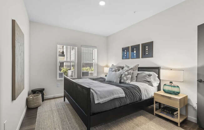 A bedroom with a large bed and a window with blinds.