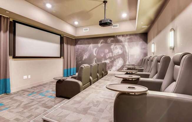 A row of grey seats are arranged in front of a screen in a room.