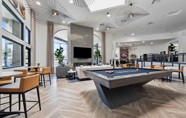 A pool table is in the middle of a room with a bar and a television.