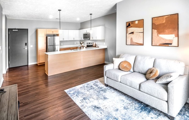 A modern living room with a white couch and a kitchen area in the background.