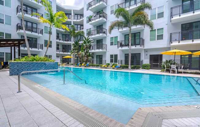 A swimming pool in front of a white building with balconies.
