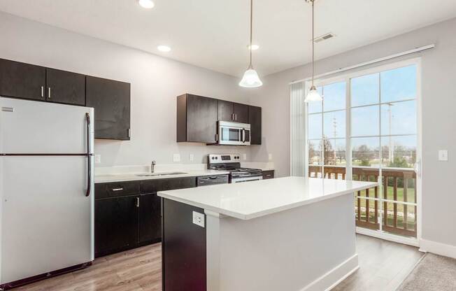 A modern kitchen with a white island and black cabinets.