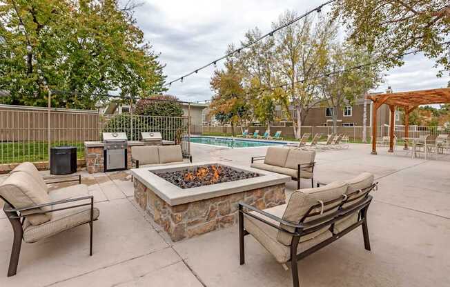A patio with a fire pit and chairs.