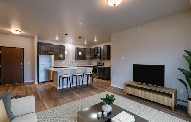 a living room with a kitchen and a tv in it. Fargo, ND Prairiewood Meadows Apartments