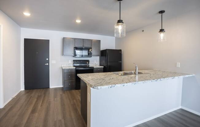Modern open-concept kitchen and living area with black appliances.
