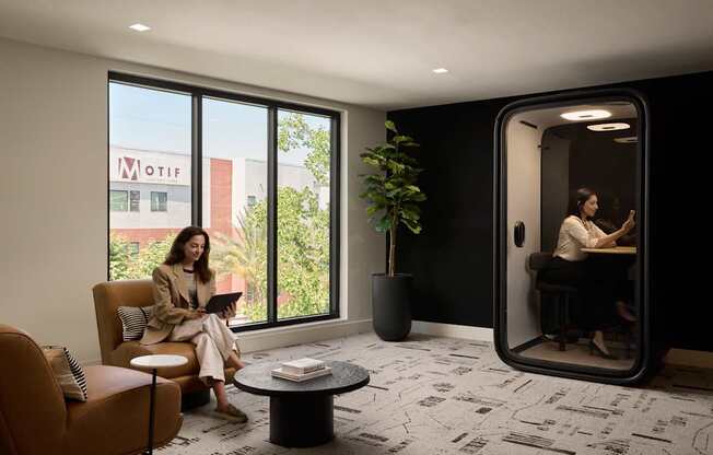 A woman is sitting on a couch in a room with a large window and a plant.