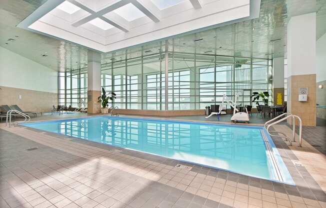 A large indoor swimming pool with sunlight streaming in through the windows.