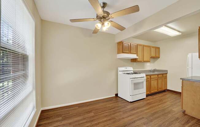 A kitchen with a white dishwasher and a white stove with wooden cabinets.