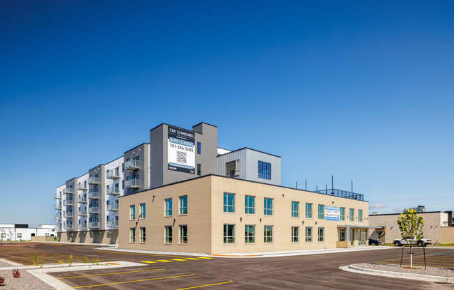 a building with a parking lot and a blue sky at The Standard on 32nd, West Fargo