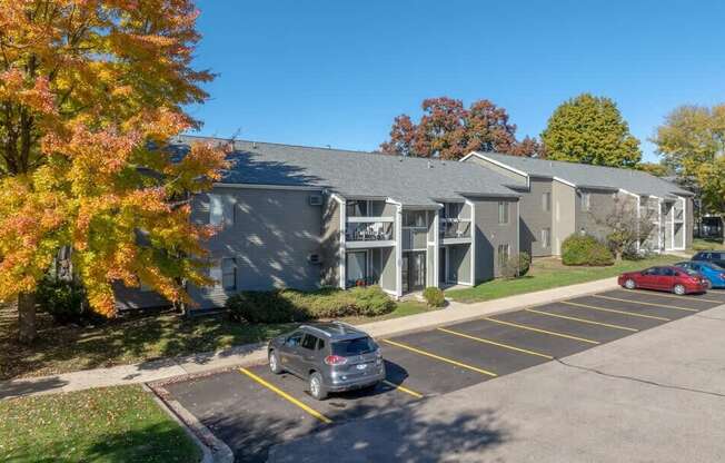 A parking lot in front of a building with a car parked in the foreground.