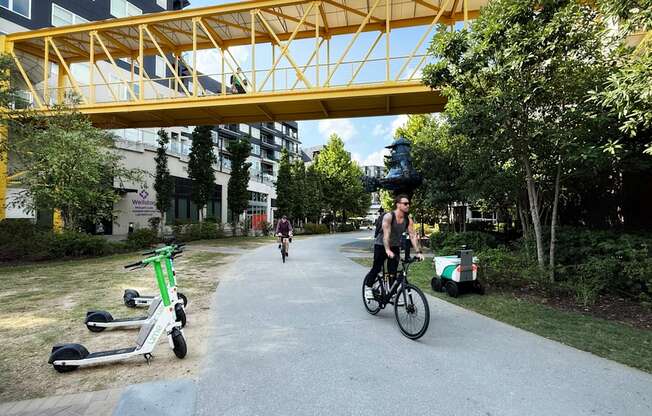 A person riding a bike under a yellow bridge in a park. at West Inman Lofts, Atlanta, Georgia
