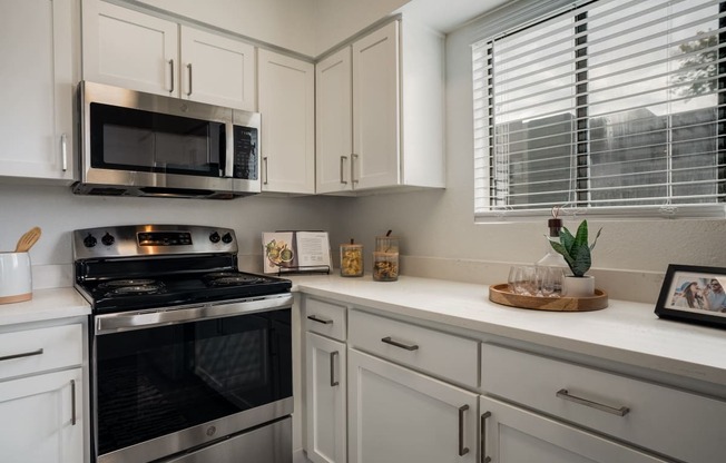 a kitchen with white cabinets and a black oven and microwave