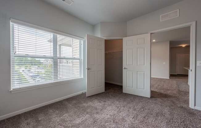 an empty bedroom with a large window and a closet