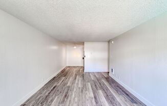 a spacious living room with hardwood floors and white walls