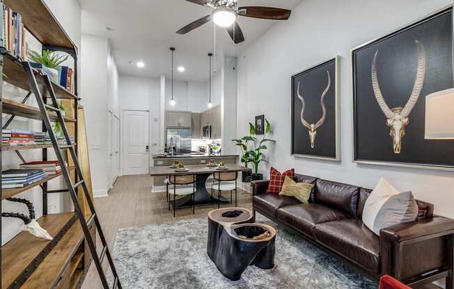 A living room with a brown leather couch and a wooden bookshelf.