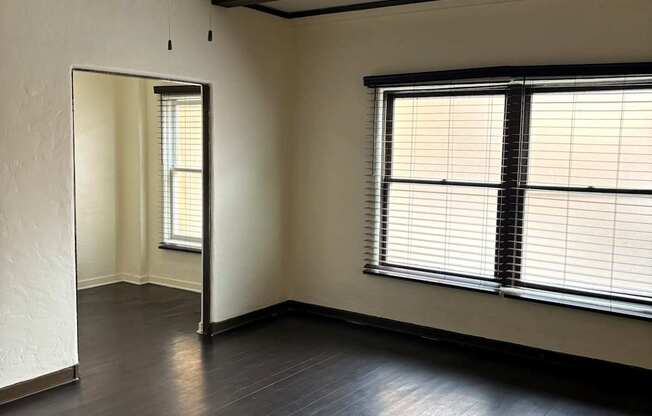 an empty living room with wood floors and a window