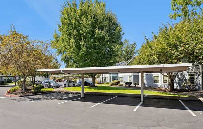 A parking lot with a white canopy and a building in the background.