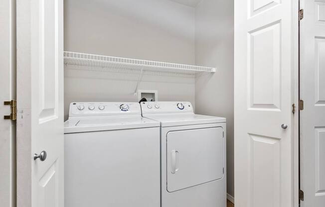 Two white washing machines in a small laundry room.