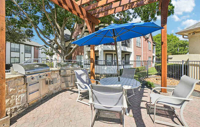 A patio with a table and chairs under a blue umbrella.
