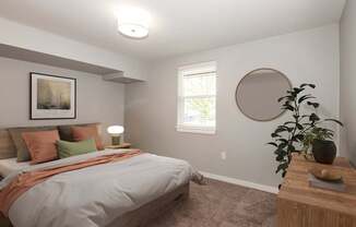 A bedroom with a bed, a lamp, a plant, and a picture on the wall.