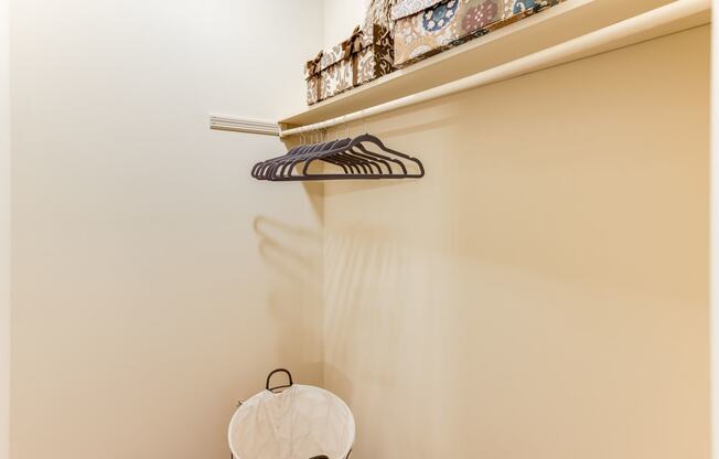 a small laundry room with a white basket and a shelf with a pair of shoes on it