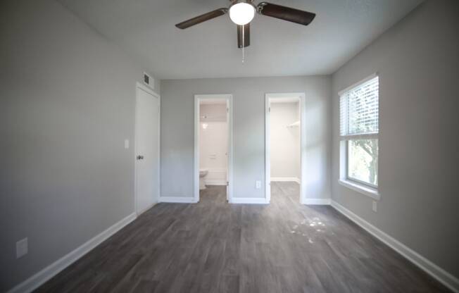 an empty living room with wood floors and a ceiling fan