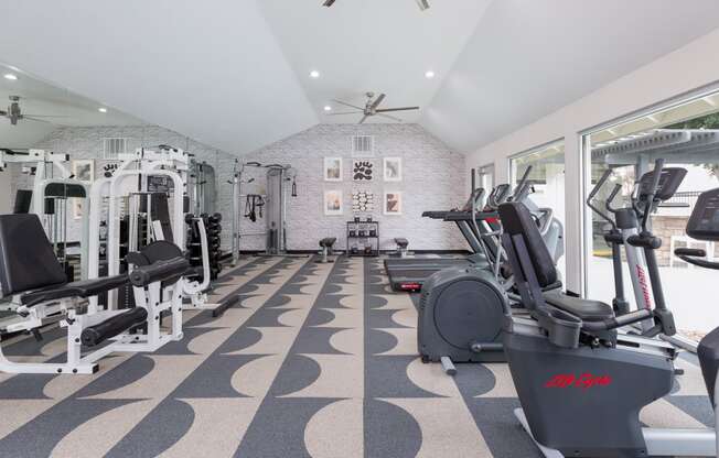 a gym with a lot of exercise equipment and a large window