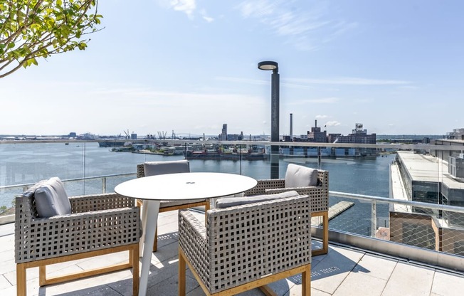 a patio with chairs and a table overlooking a river and a city