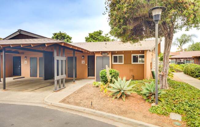 A building with a brown roof and a sign that reads "303" is surrounded by plants and trees.