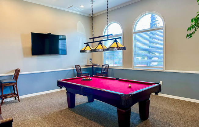 a game room with a pink pool table and a tv