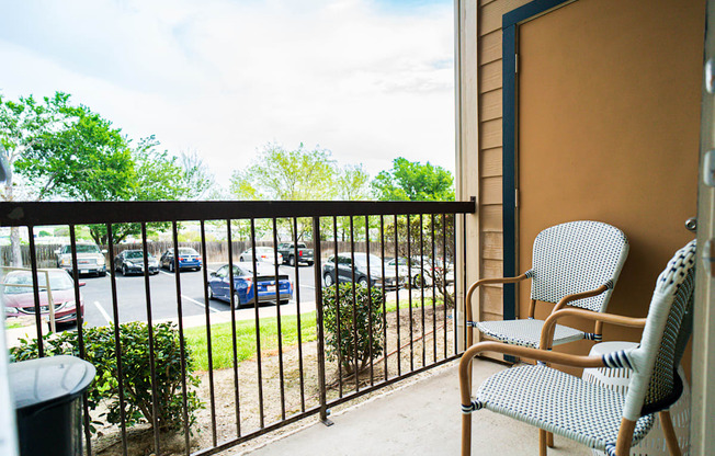 a balcony with a chair and a table and a parking lot