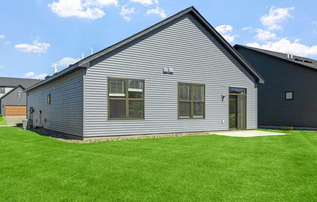 a gray house with a green lawn in front of it