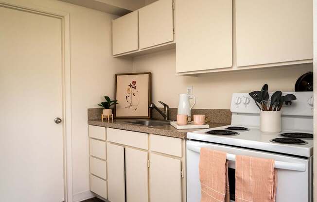 A kitchen with white cabinets and a white stove top oven.