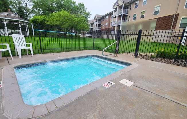 A small pool surrounded by a black fence and a white chair.