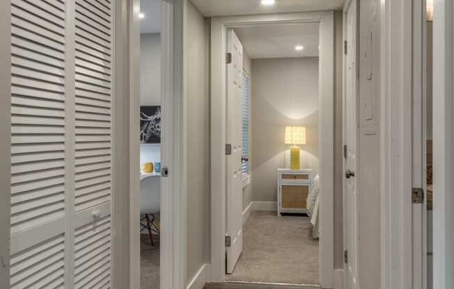 a long hallway with white doors and a bedroom in the end