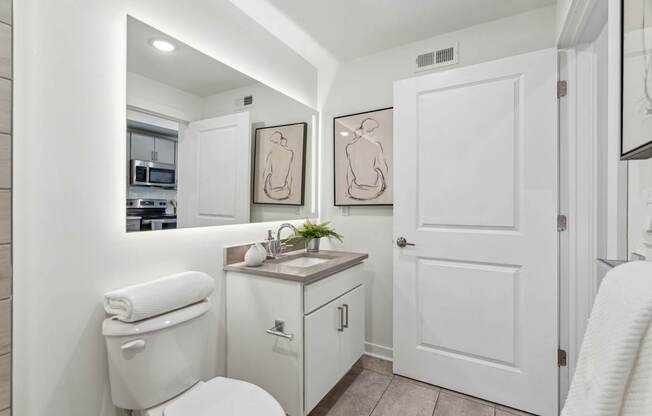 A white bathroom with a toilet, sink, and mirror.