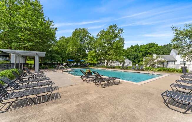 A pool area with lounge chairs and a clear blue sky.