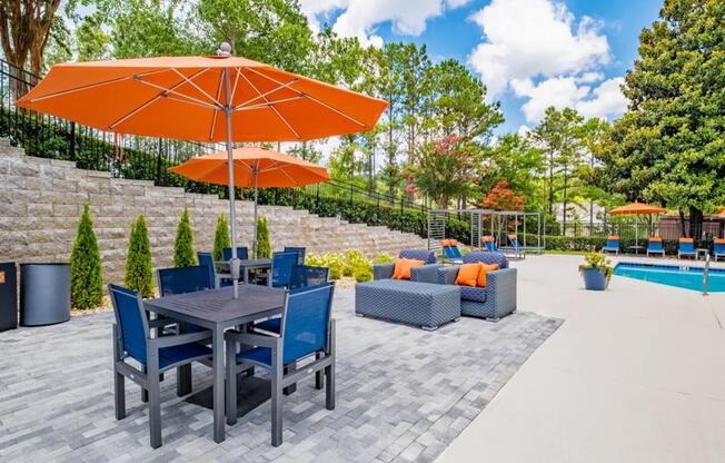 a patio with a table and chairs and an umbrella next to a swimming pool