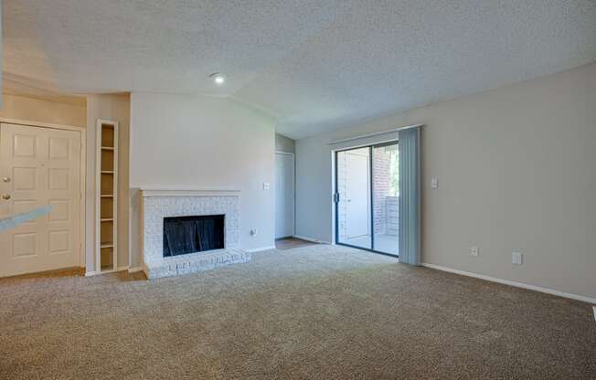 an empty living room with a fireplace and a sliding glass door