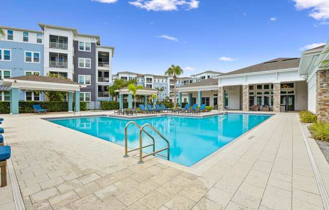 View of our swimming pool with apartment buildings in the background at Dunedin Commons apartments in Dunedin, FL