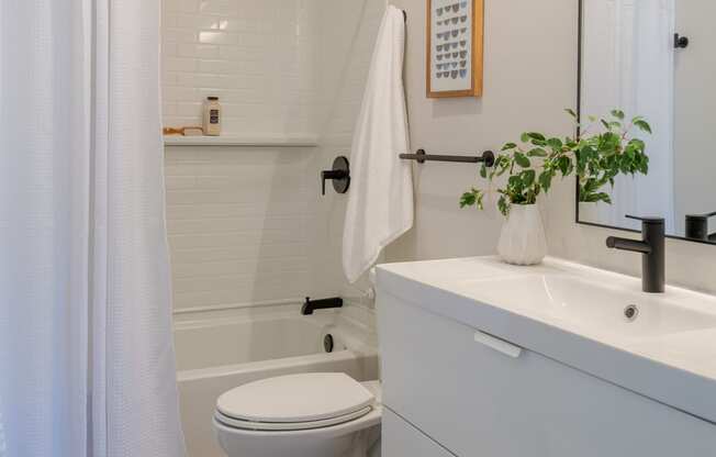 a bathroom with a white sink and toilet and a white shower curtain at The 22 Apartments, St. Louis, 63103
