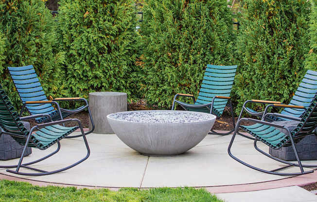 A communal outdoor patio adorned with ample seating arrangements, a cozy gas fireplace, and a fully-equipped grill ready for summer cookouts. The atmosphere radiates warmth and relaxation, offering residents a perfect setting to unwind and socialize amidst the comfort of their living space.