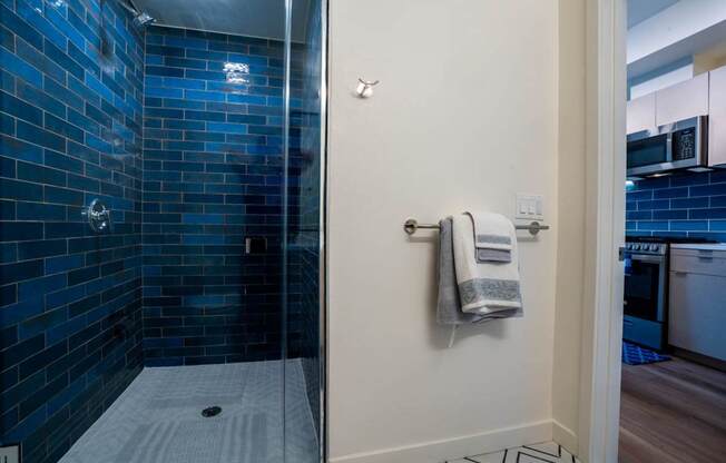 a bathroom with a glass shower and blue tiles