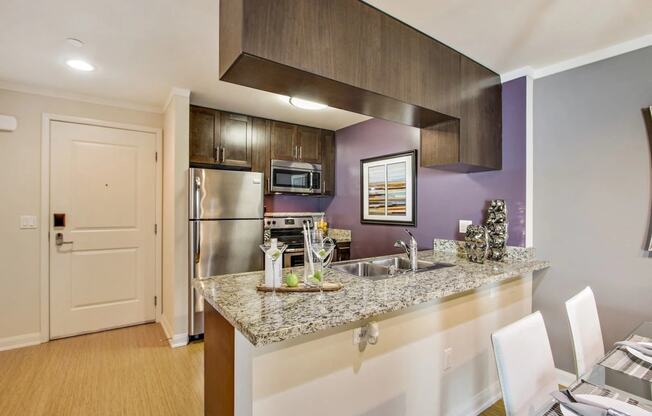 a kitchen with a granite counter top and a stainless steel refrigerator