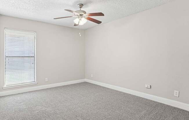 A room with a ceiling fan and carpeted floor.