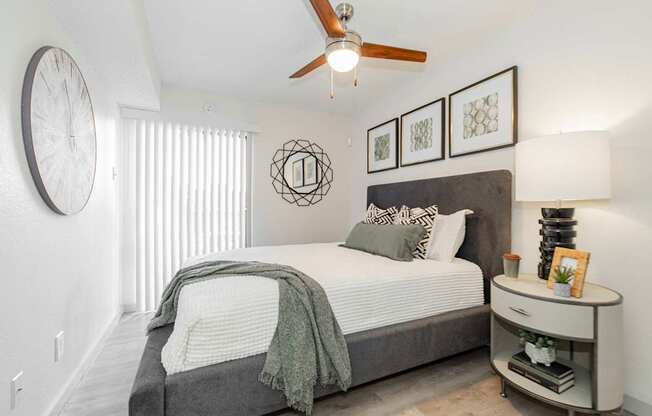A bedroom with a bed, nightstand, and a ceiling fan.